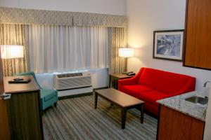 a hotel room with a red chair and a couch at Holiday Inn & Suites Denver Tech Center-Centennial, an IHG Hotel in Centennial