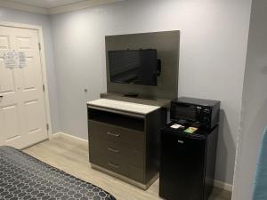 Habitación con cama, TV y escritorio. en Mirage Inn & Suites en San Francisco