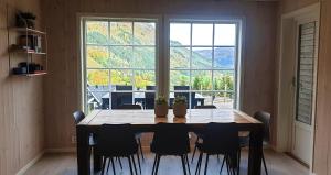 ein Esstisch mit Stühlen und ein großes Fenster in der Unterkunft New and Exclusive Cottage in Voss with a great view in Skulestadmo