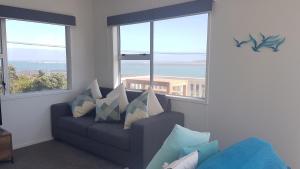 a living room with a couch and large windows at Karoro the beach front bach with views to die for! in Raglan