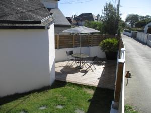 une terrasse en bois avec une table et un parasol dans l'établissement Petite maison à deux pas du centre et des plages, à Quiberon