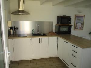 uma cozinha com armários brancos, um lavatório e um micro-ondas em Petite maison à deux pas du centre et des plages em Quiberon