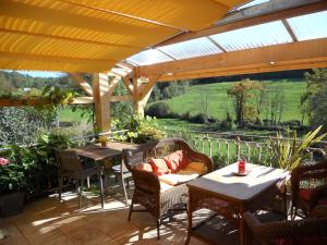 un patio extérieur avec des tables et des chaises ainsi qu'un toit dans l'établissement Le Verger Sous Les Vignes, à Villeferry