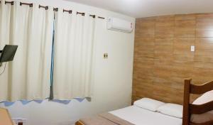Zimmer mit einem Bett und einem Fenster mit einem Vorhang in der Unterkunft Pousada Casa Grande in Bonito