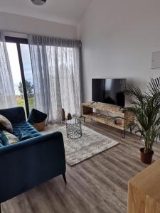 a living room with a couch and a tv at northsouthviescasinha in Calheta