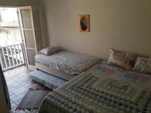 a bedroom with two twin beds and a balcony at Apartamento na enseada 50 metros da praia in Guarujá