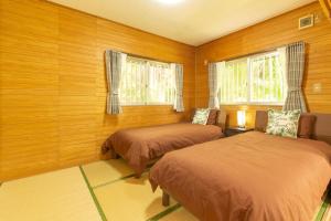 Duas camas num quarto com paredes e janelas de madeira em Villa Itona em Ishigaki Island