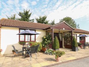 a house with a patio with chairs and an umbrella at Willow Barn in Wincanton
