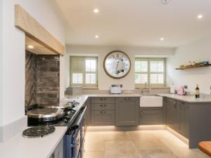 a kitchen with gray cabinets and a large clock on the wall at The Coach House in Pickering