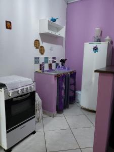 a kitchen with purple walls and a stove and a refrigerator at Pousada Sitio das Flores in Trindade