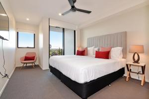 a bedroom with a large white bed with red pillows at Hedge Apartments by CLLIX in Buddina +29 photos