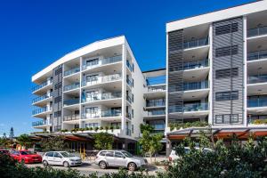 een appartementencomplex met auto's geparkeerd op een parkeerplaats bij Hedge Apartments by CLLIX in Buddina