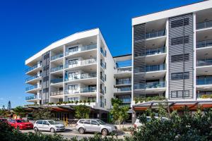 an apartment building with cars parked in a parking lot at Hedge Apartments by CLLIX in Buddina