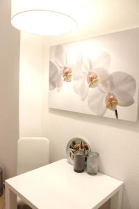une table blanche avec une photo de fleur blanche sur le mur dans l'établissement A-Partments, à Cologne