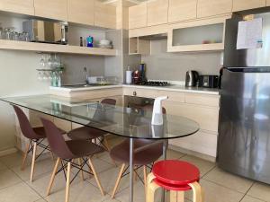 uma cozinha com uma mesa e cadeiras de vidro e um frigorífico em Departamento Laguna Bahia em Algarrobo