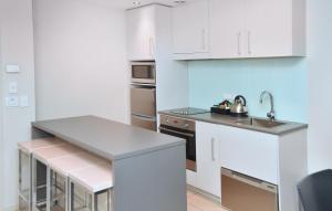 a small kitchen with white cabinets and a sink at Quest Highbrook in Auckland