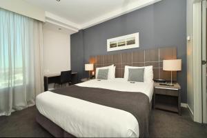 ein Hotelzimmer mit einem großen Bett und einem Schreibtisch in der Unterkunft Quest Highbrook in Auckland