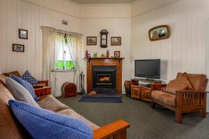 a living room with a couch and a tv and a fireplace at Dillons Cottage in Stanthorpe