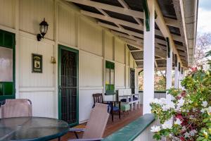 um pátio com uma mesa de vidro e cadeiras num edifício em Dillons Cottage em Stanthorpe