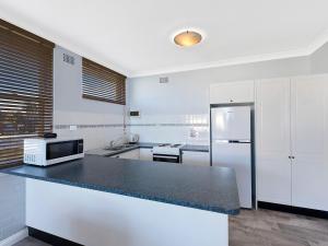 a kitchen with a black counter top and a refrigerator at Golden Sands Apartment 10 in The Entrance