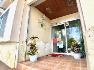 un front de magasin avec des plantes en pot devant lui dans l'établissement Time Rich, à Okinawa