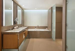 a bathroom with two sinks and a large mirror at Andaz Delhi Aerocity- Concept by Hyatt in New Delhi