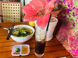 ein Getränk auf einem Tisch neben einer Schüssel Essen in der Unterkunft Mekong Rose Hotel in Cần Thơ