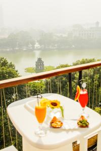 a table with two drinks on a balcony with a view at Apricot Hotel in Hanoi