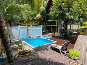 a swimming pool in a yard with a deck and a patio at Mer Riviere Self Catering Apartment in Beau Vallon