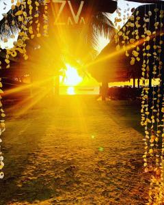 einen Sonnenuntergang am Strand mit Palmen und dem Meer in der Unterkunft Zava Nungwi in Nungwi