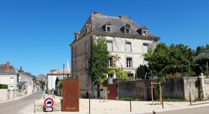 un antiguo edificio al lado de una calle en Le Voltaire, en Airvault