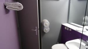a bathroom with a door with a sink and a mirror at balladins Dieppe in Saint-Aubin-sur-Scie