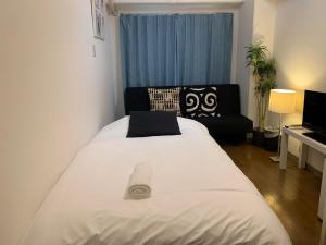 een slaapkamer met een groot wit bed en een bank bij Exsaison Shirokita 403 in Osaka