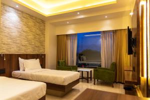 a hotel room with two beds and a living room at Hotel Pratham in Solapur