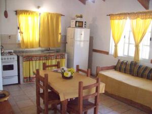 a kitchen with a table and a kitchen with yellow curtains at Complejo Sagrado Corazón in Merlo