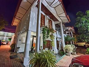 a white building with columns and plants on a street at Salubrious Resort in Anuradhapura