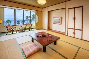 een woonkamer met een tafel en een groot raam bij Ibusuki Phoenix Hotel in Ibusuki