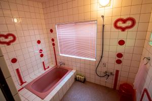 a bathroom with a tub with red hearts on the wall at Pension KUROSHIOMARU in Setouchi