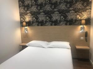 a bedroom with a large bed with a wooden headboard at Hotel de Bordeaux in Toulouse