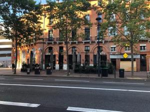 een lege straat voor een groot bakstenen gebouw bij Hotel Victor Hugo in Toulouse