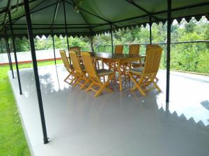 un tavolo in legno e sedie sotto un ombrellone verde di Matha Forest Resort a Purulia
