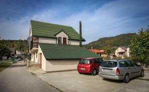 dois carros estacionados em frente a uma casa com um telhado verde em Apartments Mery em Kolašin