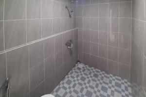 W łazience znajduje się prysznic wyłożony kafelkami i toaleta. w obiekcie RedDoorz near Alun Alun Kota Serang w mieście Gedeg