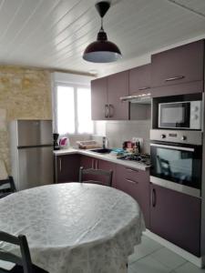 a kitchen with purple cabinets and a table in it at La Flottille, La Cotinière in La Cotinière