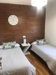 two beds in a room with wooden walls at A Fontana de Luxo Apartamentos in Portomarin