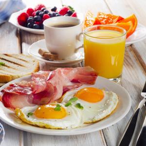 - un plateau de petit-déjeuner avec des œufs, du bacon et une tasse de café dans l'établissement Guest House Sibirskiy, à Tcheliabinsk