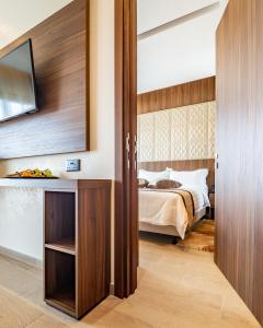 a bedroom with a bed and a television on a wall at Leonardo Boutique Hotel Larnaca in Larnaca