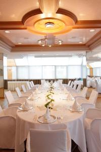 a large banquet hall with white tables and white chairs at Hotel Gude in Kassel