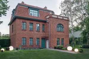 a large red brick building with a green door at Pensjonat Victoria by OneApartments in Sopot