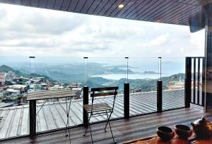 uma cadeira e uma mesa numa varanda com vista em Dosun B&B em Jiufen